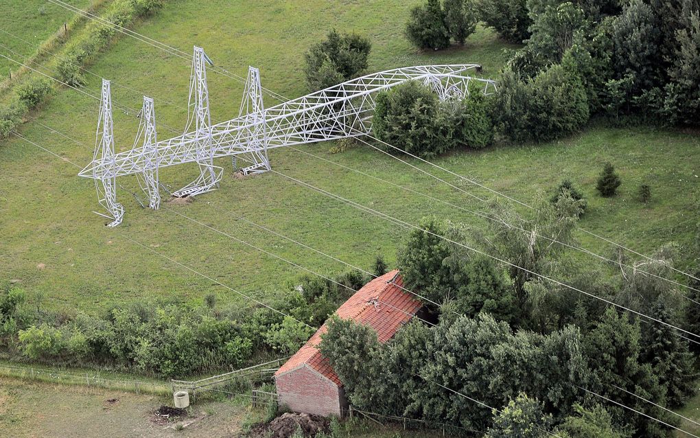 Een elektriciteitsmast ligt donderdag geknakt op het land in de omgeving van Vethuizen (Gelderland). Het dorp werd woensdag getroffen door een windhoos die een spoor van vernielingen aanrichtte. Foto ANP