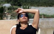 NAHR AL BARED – Een Libanese vrouw geniet ongestoord van de zomerzon terwijl achter haar grote rookpluimen opstijgen vanuit het Palestijnse vluchtelingenkamp Nahr al Bared. De gevechten in het kamp tussen het Libanese leger en islamitische radicalen ginge