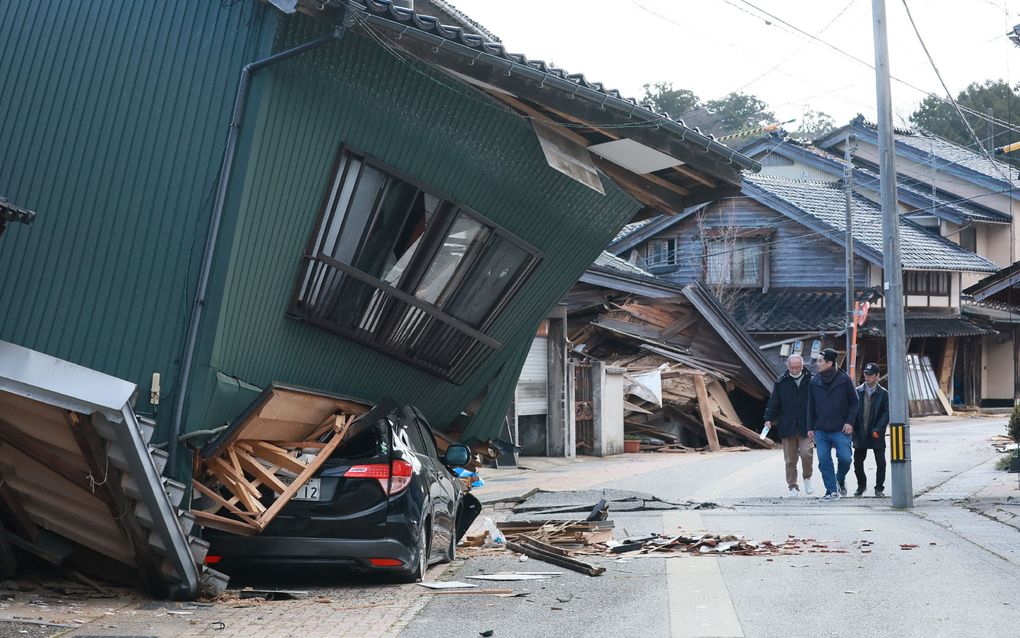 Voetgangers passeren dinsdag een zwaar beschadigd huis in Nanao, een stad in de prefectuur Ishikawa. Op nieuwjaarsdag troffen meer dan 150 aardbevingen Japan. De zwaarste had een kracht van 7,6. beeld AFP, Jiji Press