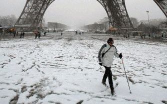 PARIJS - In Frankrijk is in de nacht van zaterdag op zondag een pak sneeuw gevallen. Op de foto loopt in Parijs een Fransman onder de Eiffeltoren door. - Foto EPA