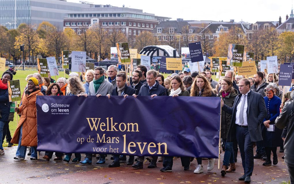 De stoet aanwezigen tijdens de stille protestmars door het centrum van Den Haag. Vooraan lopen onder meer CU-lijsttrekker Mirjam Bikker en de top drie van de SGP-kandidatenlijst voor de Tweede Kamerverkiezingen. beeld Dirk Hol