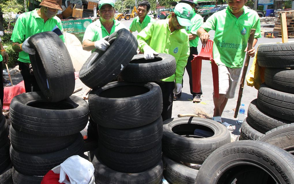 BANGKOK - Thaise gemeentewerkers ruimen vrijdag bandenstapels op na de protesten in Bangkok. Foto EPA