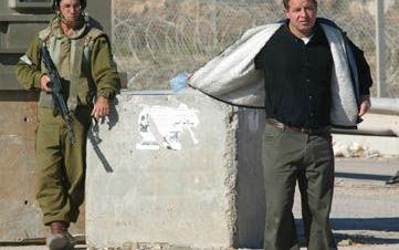 KALANDIA - Een Palestijn toont aan een IsraÃ«lische soldaat bij een controlepost op de weg tussen Jeruzalem en Ramallah dat hij geen explosieven om zijn middel draagt. - Foto EPA