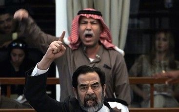 BAGDAD - Met opgeheven vinger protesteert Saddam Hussein, voormalig president van Irak, zondag tegen het tegen hem uitgesproken doodvonnis. Fofo EPA