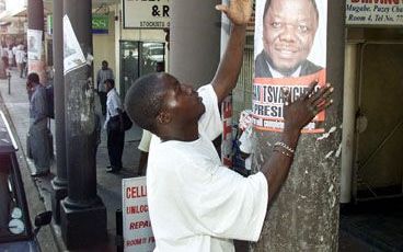 HARARE - Een aanhanger van de Zimbabwaanse oppositiepartij Beweging voor Democratische Verandering plakt een verkiezingsaffiche op in het centrum van de hoofdstad Harare. Op 9 en 10 maart worden in Zimbabwe verkiezingen gehouden. - Foto EPA