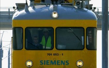 BREDA â€“ De TVT testtrein van Siemens aan het werk op de HSL Zuid bij Breda Prinsenbeek. Op het platform staan twee mannen met enorme ringsleutels en ander gereedschap. Elk ophang punt van de rijdraad â€“onderdeel van de bovenleidingâ€“ wordt nog even na