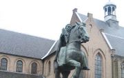 UTRECHT– Drs. Jaap van Vredendaal voor het standbeeld van Willibrord in Utrecht. De kerstening in de Lage Landen was niet alleen een politiek proces. „Het Ierse christendom, waaruit Willibrord afkomstig was, had een sterk ascetische en spirituele inslag.”