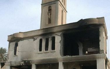 BAGDAD - Een Iraakse vrouw loopt langs een zwaar beschadigde kerk in Bagdad. Onbekenden pleegden zaterdagochtend aanslagen op zes kerken in de Iraakse hoofdstad. Foto EPA