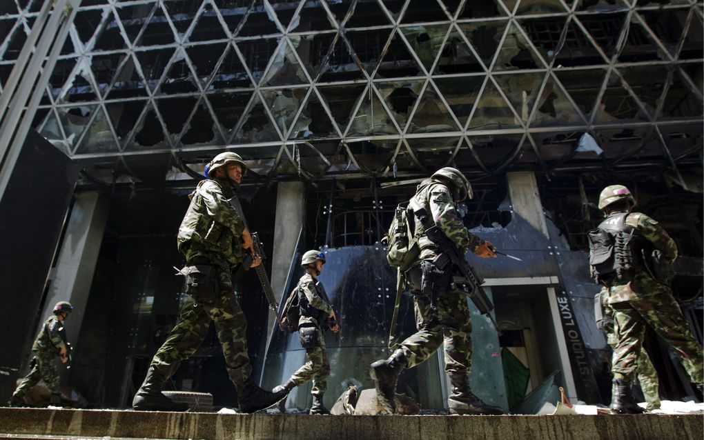 BANGKOK - Thaise militairen lopen door een uitgebrand winkelcentrum. Foto EPA