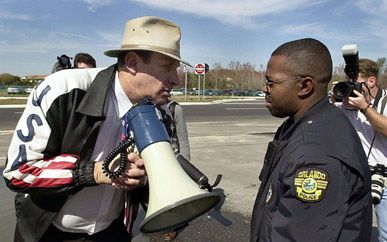 ORLANDO â€“ Archieffoto van 05 februari 2001 laat een politieofficier uit Orlando zien, die voorzitter Irv Rubin van de Jewish Defense League (JDL), vraagt om te stoppen met het gebruik van zijn megafoon tijdens een protestactie bij de opening van het ”Ho