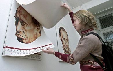 MOSKOU â€“ Een meisje bekeek dinsdag de Poetin-kalender voor 2002: iedere maand een ander getekend portret van de Russische president. - Foto EPA