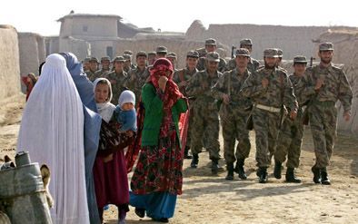 AL KHANUM â€“ Soldaten van de Noordelijke Alliantie passeren in het dorp Al Khanum, op weg naar het front, een groep Afghaanse vrouwen en meisjes. De Noordelijke Alliantie zet haar opmars in Afghanistan gestaag voort. De helft van het Afghaanse grondgebie