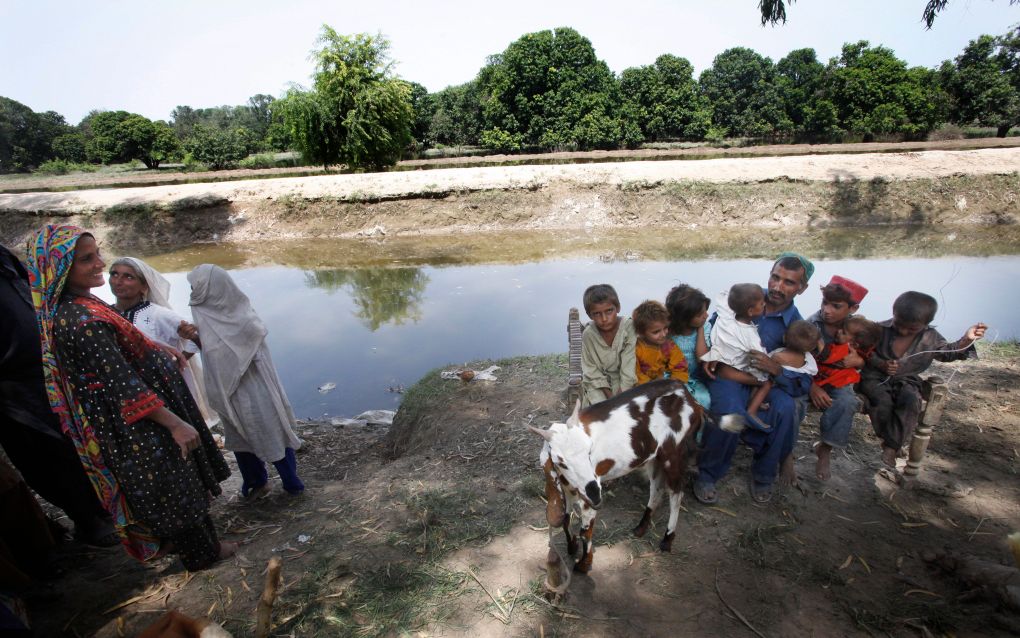 Kamperen in de berm. Nawaz poseert in Rahimyar Khan met zijn kinderen en geit. Wadi (l.) kijkt lachend toe, maar mag vanwege de islamitische regels eigenlijk niet op de foto. Foto Jaco Klamer