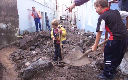 Jongens helpen opruimen op het eiland Tenerife, dat onlangs door een wervelstorm werd getroffen. - Foto EPA