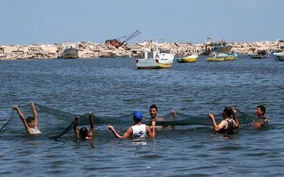 GAZA â€“ Palestijnse vissers gooien hun net in het water voor het strand van Gaza. Als gevolg van de IsraÃ«lische inval in de Gazastrook mogen de vissers nog maar tot 4 meter van de kust vissen in plaats van de gebruikelijke 10 kilometer. Foto EPA