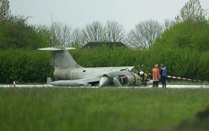 LEEUWARDEN - Hulpverleners bekijken het wrak van de neergestorte F-104 Starfighter op de vliegbasis Leeuwarden. Het gevechtsvliegtuig stortte daar donderdagmiddag neer, vermoedelijk doordat de Italiaanse piloot de landing te laag had ingezet. - Foto ANP