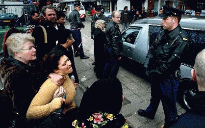 DEN HAAG - In Den Haag is dinsdagmorgen tijdens een arrestatie een verdachte doodgeschoten. Een zus (l.) van het slachtoffer reageerde geÃ«motioneerd toen de lijkwagen voorbijreed. Het slachtoffer was een van de twee verdachten van een omvangrijke fraude.