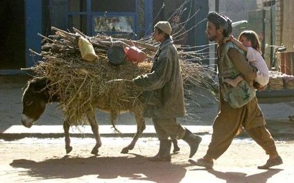 TALOQAN â€“ Een Afghaanse vluchteling draagt zijn dochtertje op de rug bij zijn terugkeer naar Taloqan, de stad die twee dagen geleden in handen kwam van de Noordelijke Alliantie. - Foto EPA