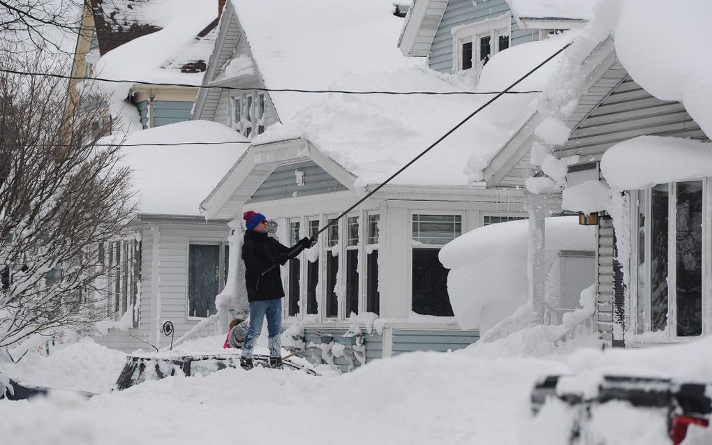 Een man probeert zijn dak sneeuwvrij te maken in Buffalo, New York. beeld AFP, John Normile