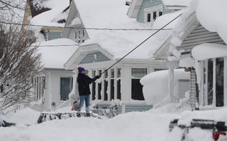 Een man probeert zijn dak sneeuwvrij te maken in Buffalo, New York. beeld AFP, John Normile