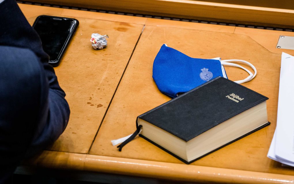 Een mondkapje en een Bijbel tijdens het plenair debat in de Tweede Kamer over de ontwikkelingen rondom het coronavirus. beeld ANP, Bart Maat