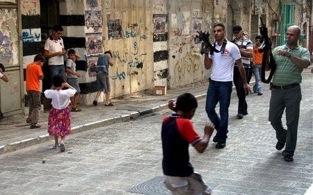 NABLUS – Palestijnse kinderen rennen weg als leden van de al Aqsa Martenlaren Brigades hun wapens afvuren in de straten van Nablus. Zowel op de Westelijke Jordaanoever als in de Gazastrook braken vrijdag ongeregeldheden uit. Foto EPA