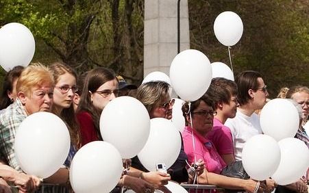 Toeschouwers met witte ballonnen hebben zich donderdag verzameld in Apeldoorn bij het herinneringsmonument voor de slachtoffers van het koninginnedagdrama vorig jaar. Foto ANP