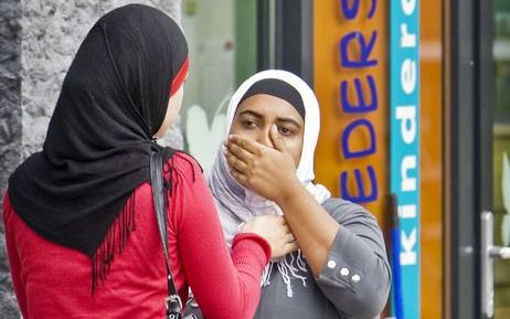 Twee vrouwen troosten elkaar voor het kinderdagverblijf Moeders Schoot in Amsterdam. Foto ANP