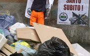 NAPELS - Een man hangt een protestaffiche op bij een stapel afval. In deze Zuid-Italiaanse stad wordt al maanden geen huisvuil opgehaald wat zorgt voor een enorme stankoverlast. Foto EPA