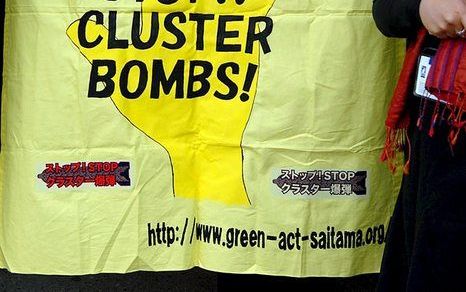 DUBLIN - Een vrouw toont een spandoek met de tekst ”Stop clusterbommen!", maandag in Dublin. Foto EPA