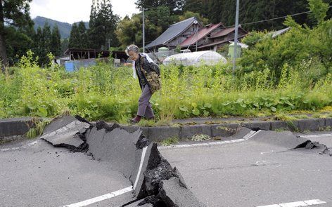 TOKIO - Een oudere vrouw passeert een weg bij Ichinoseki die ook getroffen is door de beving. Foto EPA