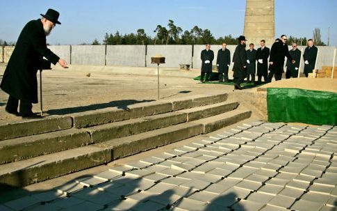 ORANIENBURG â€“ Een rabbijn strooit zand uit over de plaats waar 150 urnen met elk 30 kilo as een plaats hebben gekregen. Tijdens een ceremonie hebben overlevenden van het nazi concentratiekamp Sachsenhausen dinsdag de as van duizenden van hun omgekomen m