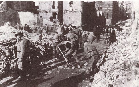 NIJMEGEN â€“ De Nederlandse Arbeidsdienst ruimt in Nijmegen de puinhopen op. Op 22 februari 1944 werd de stad â€“hoogstwaarschijnlijk door een vergissingâ€“ gebombardeerd door Amerikaanse bommenwerpers. Foto Kroniek van Nederland