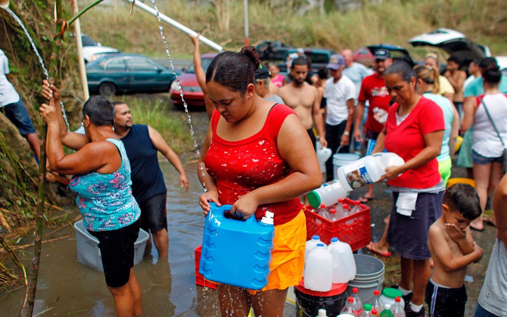 Mensen halen water bij een bron op het eiland Puerto Rico, dat grote schade heeft opgelopen door de orkaan Maria. beeld AFP