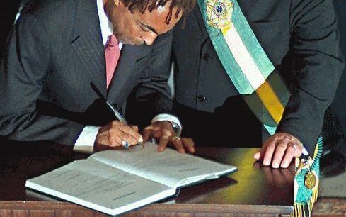 BRASILIA - De zonet beÃ«digde Braziliaanse president Luiz Inácio da Silva (r.) kijkt toe hoe zijn nieuwe minister van Cultuur, Gilberto Gil, het inauguratieboek tekent. - Foto EPA