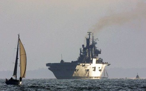 PORTSMOUTH - Een klein zeiljachtje voer zaterdag terug naar de haven van Portsmouth toen het marineschip Ark Royal juist wegstoomde. Het vliegdekschip vaart naar de Middellandse Zee en het Verre Oosten voor militaire oefeningen. De tocht houdt verband met