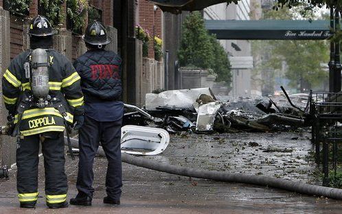 NEW YORK - Brandweermannen kijken naar de wrakstukken van het vliegtuigje voor het flatgebouw. Foto EPA