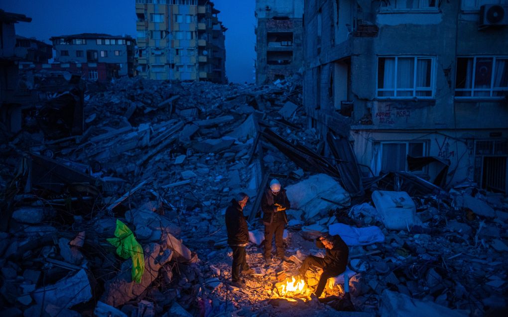 Een klein lichtpuntje in de duisternis; Turkse reddingswerkers warmen zich na aardbeving aan een vuurtje. beeld EPA, Martin Divisek