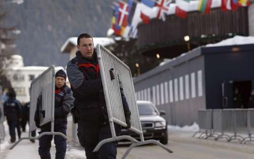 DAVOS - Politiemensen dragen dranghekken weg bij het congresgebouw in het Zwitserse Davos. Het World Economic Forum eindigde zondag met afspraken over onderhandelingen om de wereldhandel verder vrij te geven. - Foto EPA