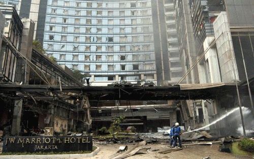 JAKARTA - Brandweerlieden blussen een klein brandje dat nog oplaait na de bomaanslag bij het Marriott Hotel in de Indonesische hoofdstad Jakarta. Bij de explosie kwamen volgens de laatste berichten van de politie geen veertien maar negen mensen om het lev