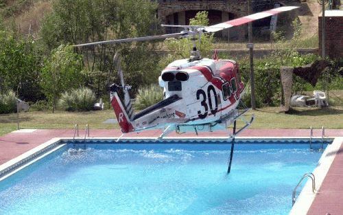 BARCELONA - Een helikopter van de Spaanse brandweer haalt water op bij een particulier zwembad om bosbranden te blussen. - Foto EPA