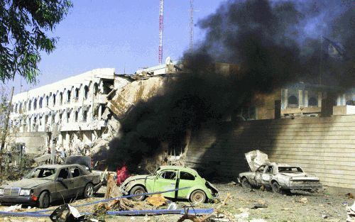 Bagdad - Rookwolken stijgen op van brandende auto’s naast het verwoeste VN hoofdkwartier in Bagdad. Zeker zeventien mensen werden dinsdagmiddag gedood toen een zware autobom bij het gebouw ontplofte. Foto: AFP