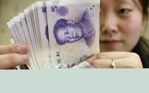 PEKING - Een Chinese bankmedewerkster telt geld. China staat onder toenemende druk om de koers van zijn munteenheid, de yuan, omhoog te brengen. Volgens de VS en andere landen is de huidige koers te laag. Foto AFP