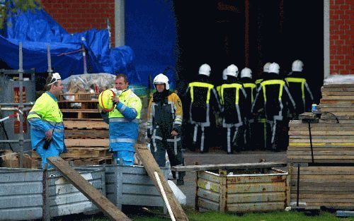 GEERTRUIDENBERG - Brandweerlieden betreden het gebouw van de Amercentrale in Geertruidenberg waar acht onderhoudsmedewerkers in een lege stoomketel zijn gevallen. Op de voorgrond wacht het ambulancepersoneel. - Foto ANP