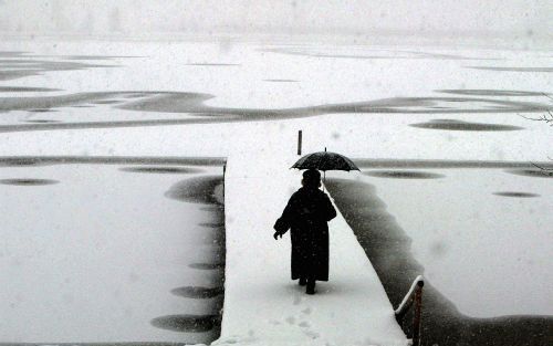 AITRANG â€“ Sneeuwval zorgde maandag in Europa voor grote problemen op de wegen, maar gaf ook prachtige beelden, zoals hier in het Duitse Beieren, waar een vrouw de aanlegsteiger bij een meertje oploopt. Foto EPA