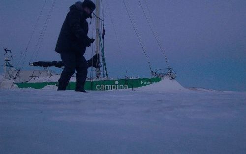 TIKSI â€“ Zeezeiler Henk de Velde bij zijn ingevroren jacht Campina. De wereld om hem heen is een uitgestrekte ijsvlakte. „Dit glorieuze arctische land leert mij geduld te hebben. Volharding is mijn enige bondgenoot.” Foto Campina