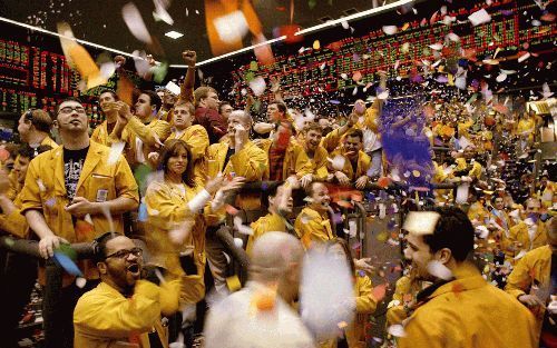 CHICAGO - Beurshandelaren werden op oudejaarsdag bedolven onder de confetti bij het sluiten van de beurshandel op de Chicago Mercantile Exchange. - Foto EPA