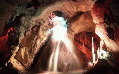 Grillig gevormde stalagmieten en een neerstortende waterval in de Grottes de Neptune.