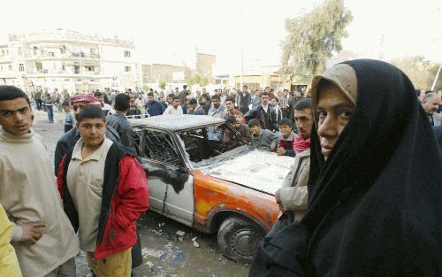 BAQUBA - Inwoners van de Iraakse stad Baquba verzamelen zich rond een verwoeste taxi na de ontploffing van een bom voor een sjiitische moskee. Bij de aanslag van vrijdag kwamen minstens vijf mensen om het leven en raakten nog eens 38 anderen gewond. Een b