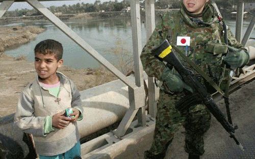 SAMAWA â€“ Een lid van de Japanse defensiemacht in het zuiden van Irak poseerde maandag met een Iraakse jongen. De Japanse soldaten worden door het thuisfront nauwlettend gevolgd, want voor het eerst sinds de Tweede Oorlog heeft Japan grondtroepen naar ee